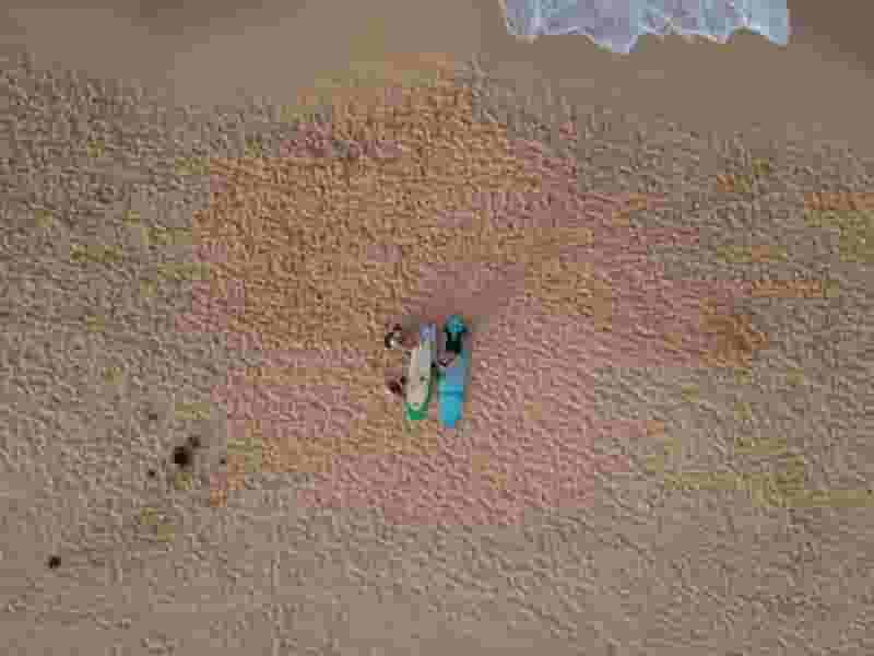 drone shot of surfers on beach