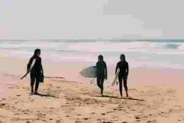 surfers walking on beach